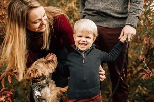 Little boy with mom, dad, and puppy, laughing and having fun