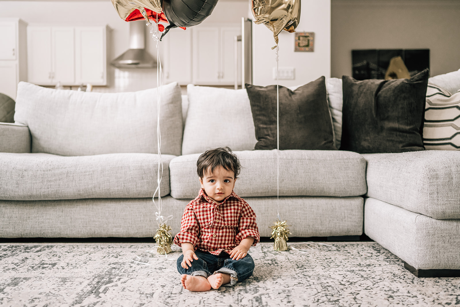 Toddler sitting on living room floor during milestone session, part of the first year of newborn photos.