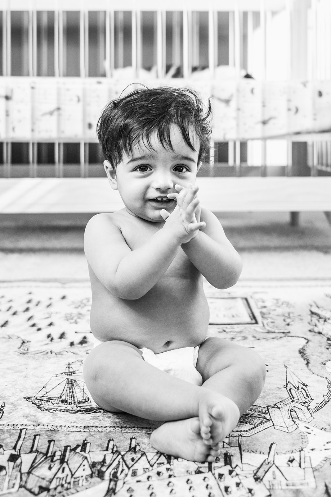 Black and white portrait of baby clapping hands during milestone session in the first year of newborn photos.