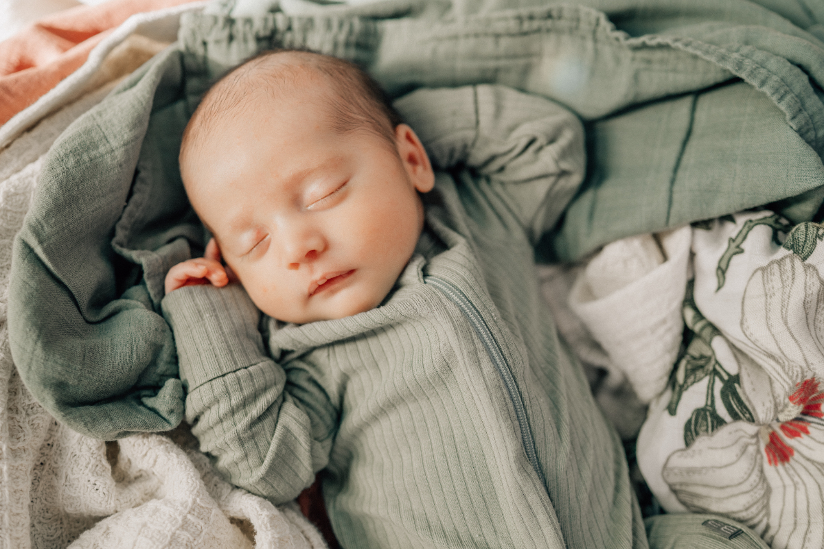 Sleeping newborn wrapped in a soft blanket, photographed in natural light during an in-home newborn photography session.