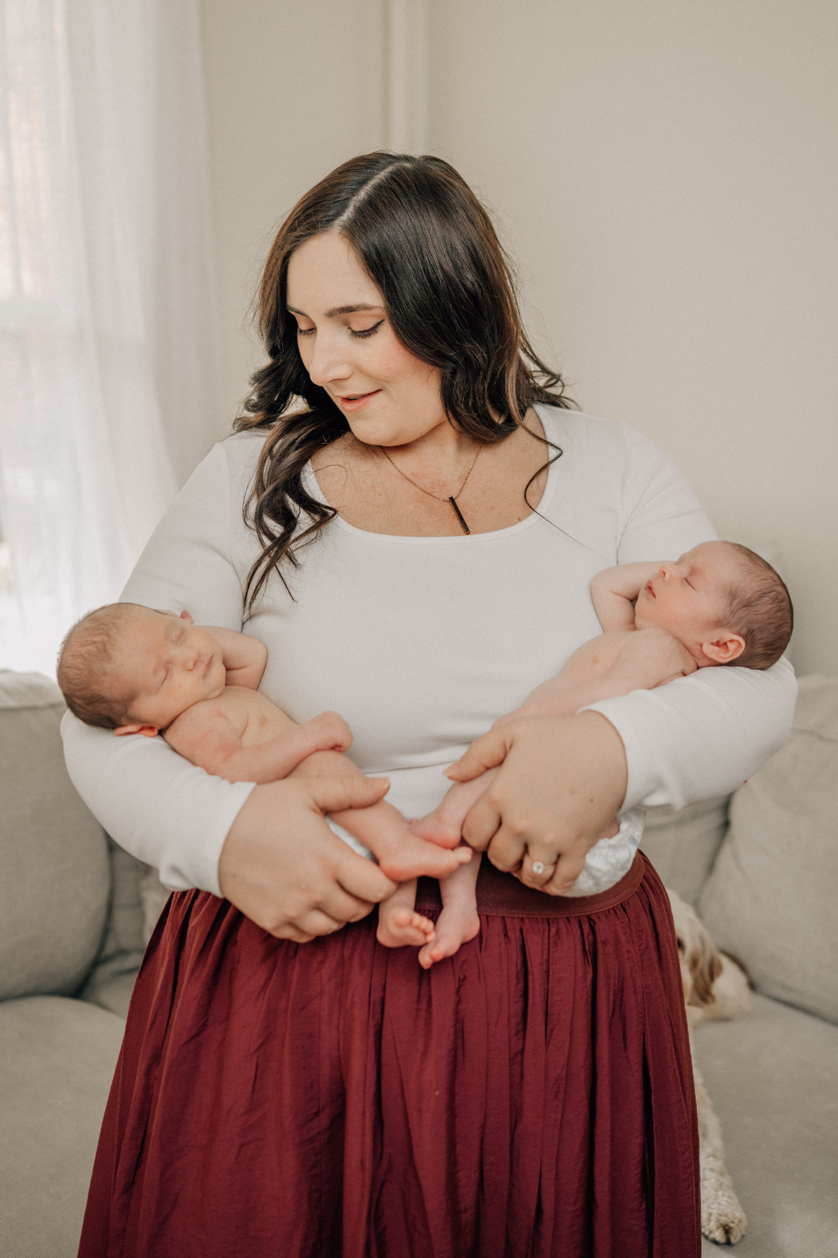 Mother holding her newborn in her arms on the couch during a relaxed in-home newborn photography session.