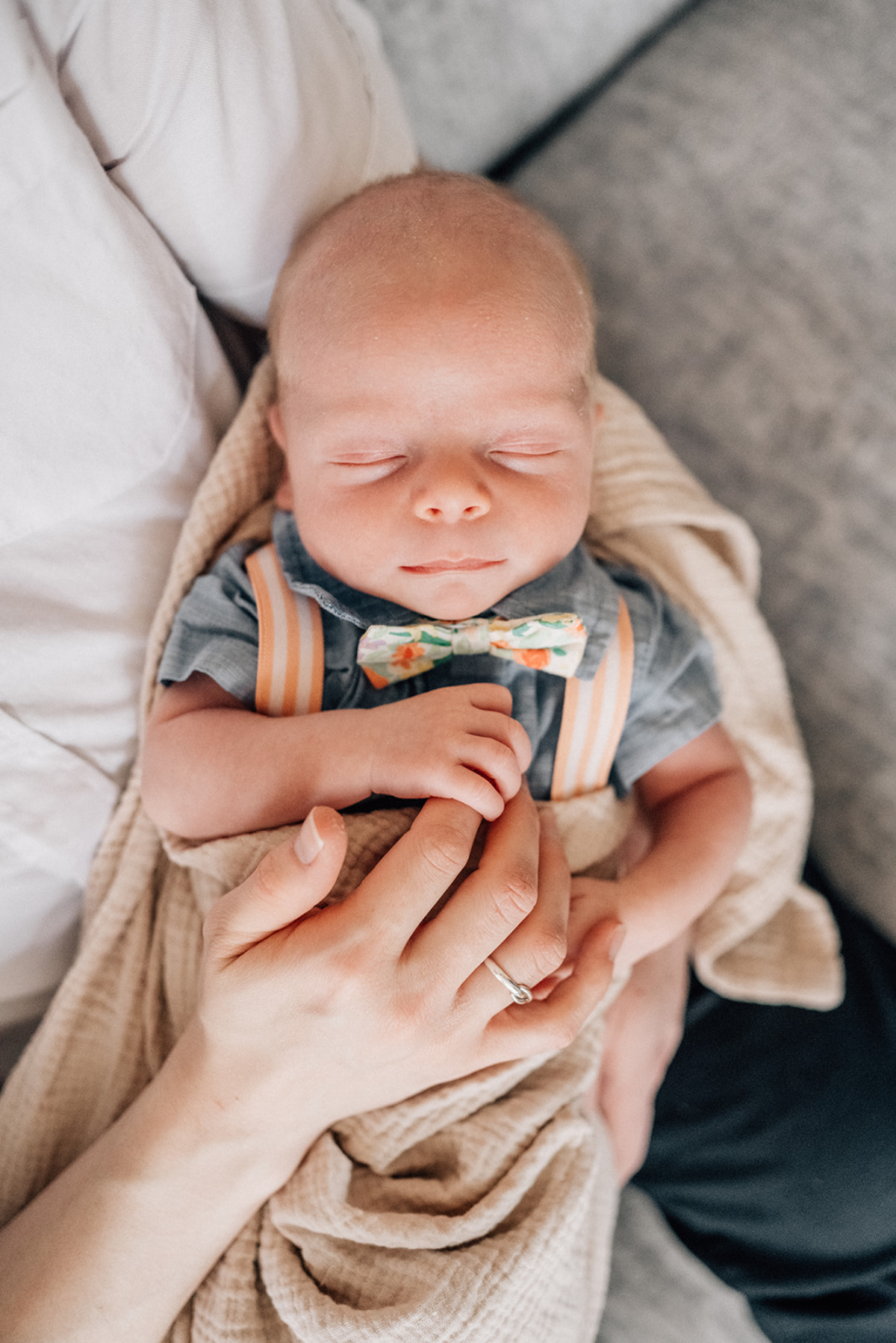 Sleeping newborn lying on parent’s chest during milestone photography session, capturing calm connection and early newborn days.