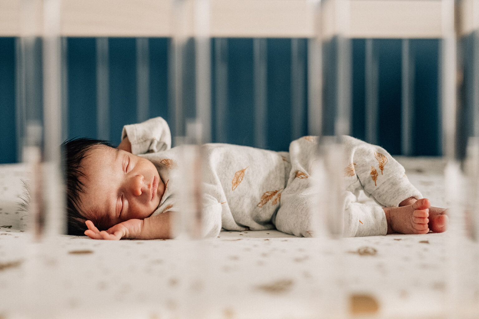 Newborn sleeping in crib during in-home session, part of the first year of newborn photos.