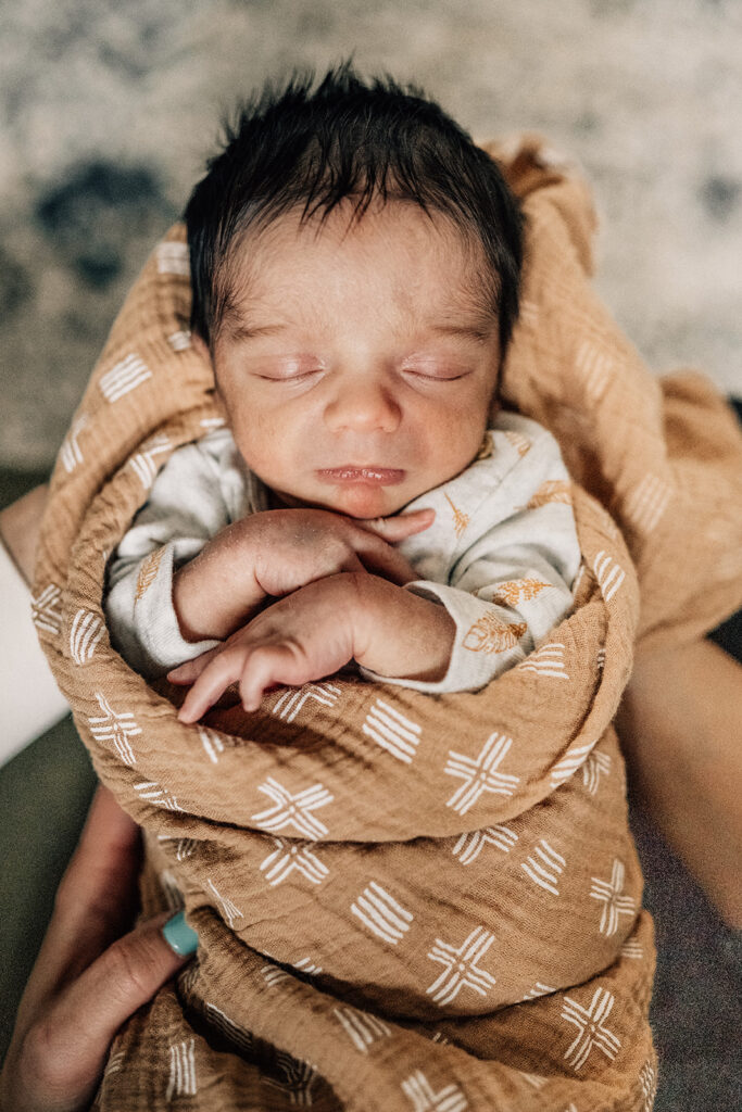 Sleeping newborn wrapped in blanket during in-home session, part of the first year of newborn photos.