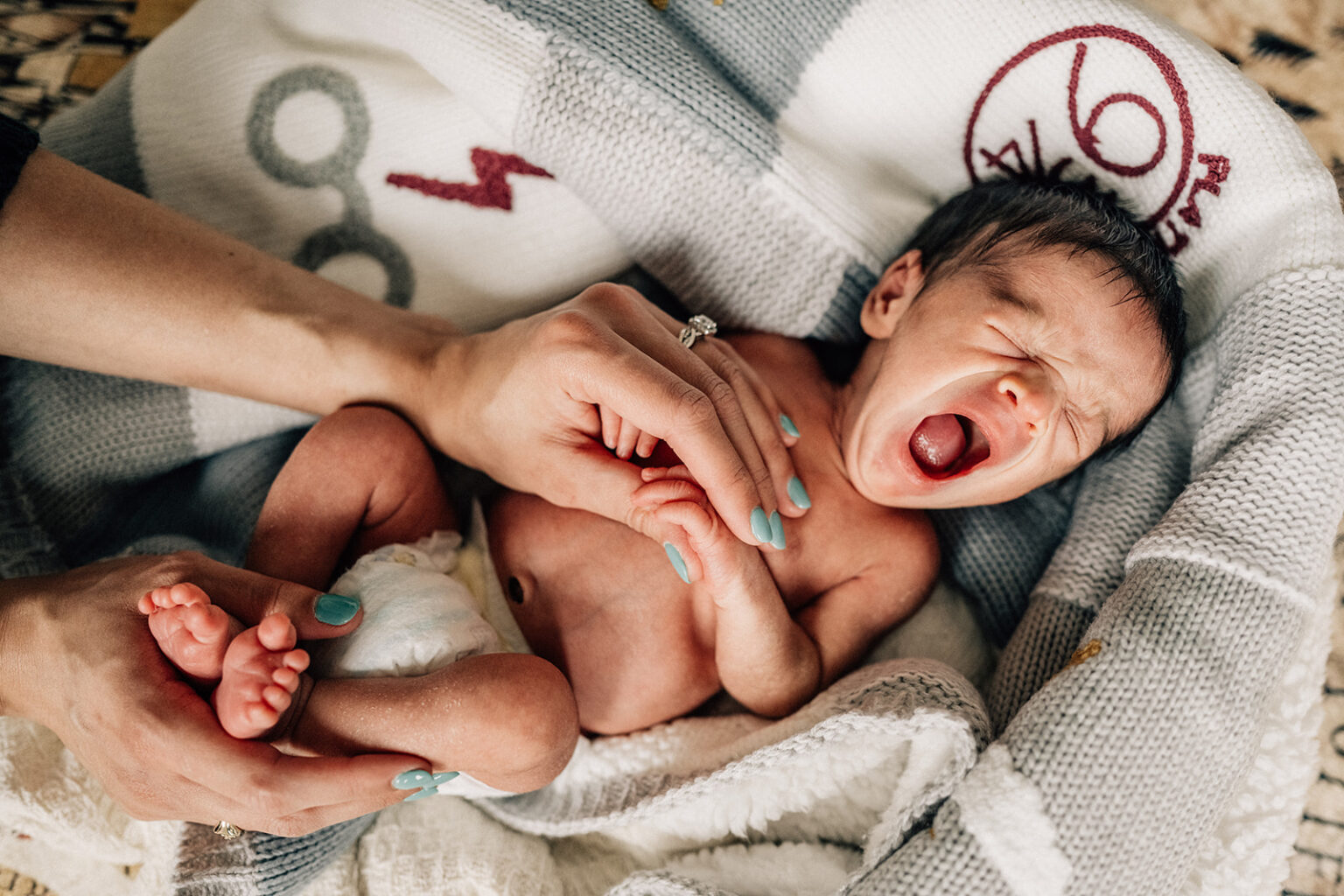 Newborn crying during lifestyle session at home, capturing real moments from the first year of newborn photos.