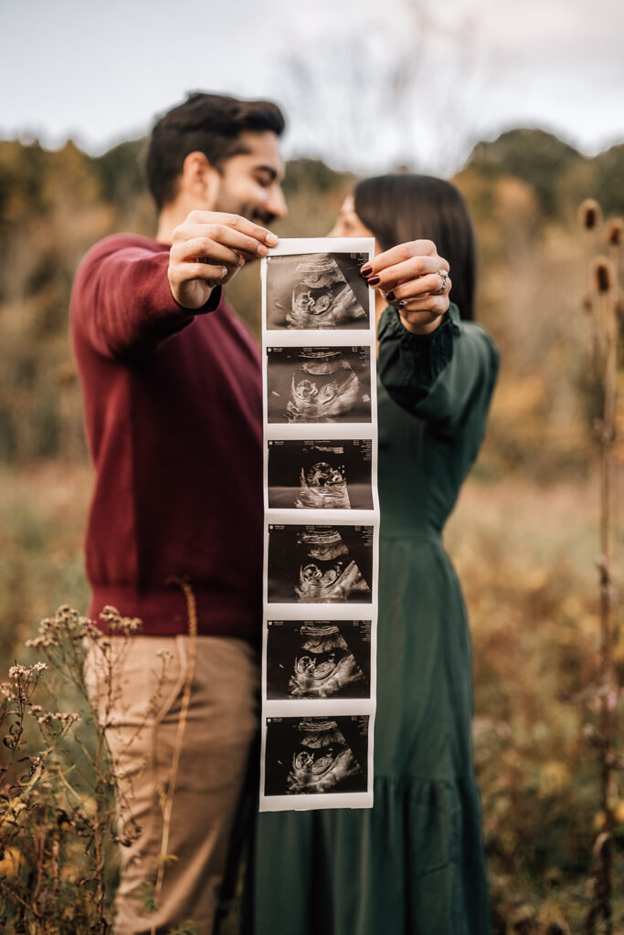 Expecting parents holding ultrasound photos during pregnancy session, starting the first year of newborn photos.