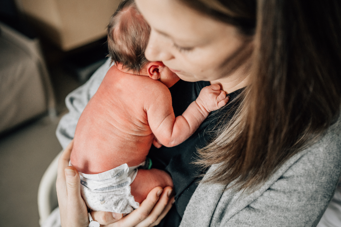 Mother holding newborn skin to skin in a hospital room, capturing connection and emotion in the first hours after birth.