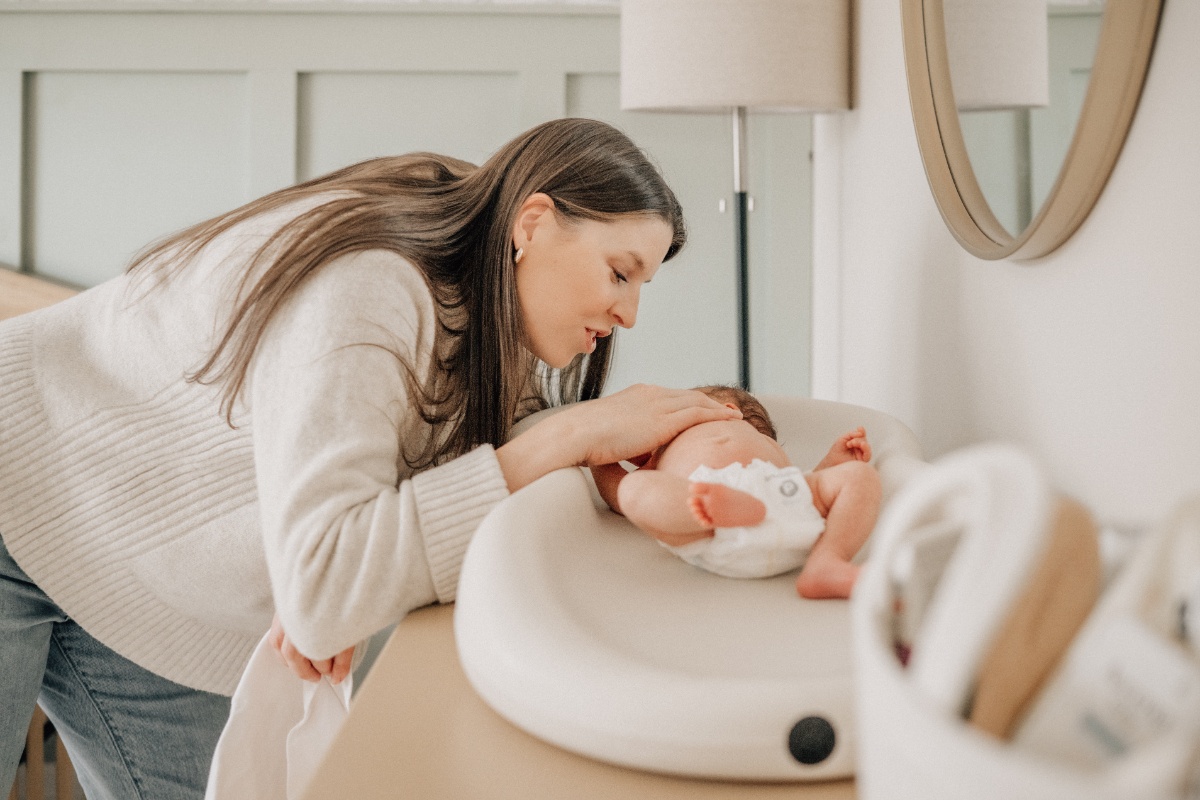 In-home newborn baby photos of mom leaning over baby in crib.