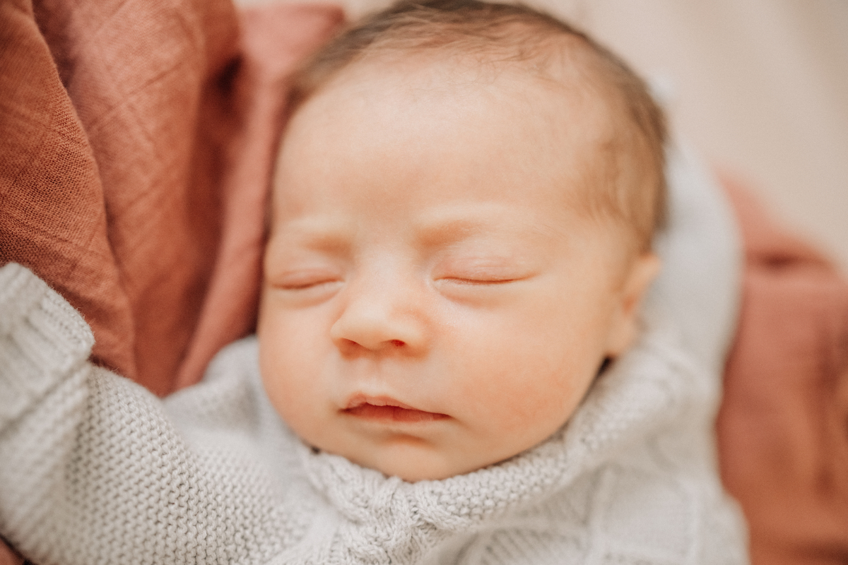 Cozy newborn baby photos of sleeping baby wrapped in warm blanket.