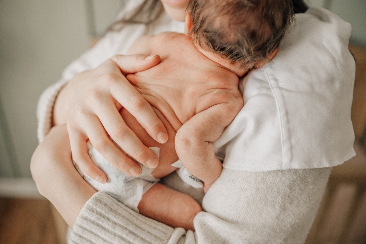 Lifestyle newborn baby photos of parent holding newborn close on shoulder.