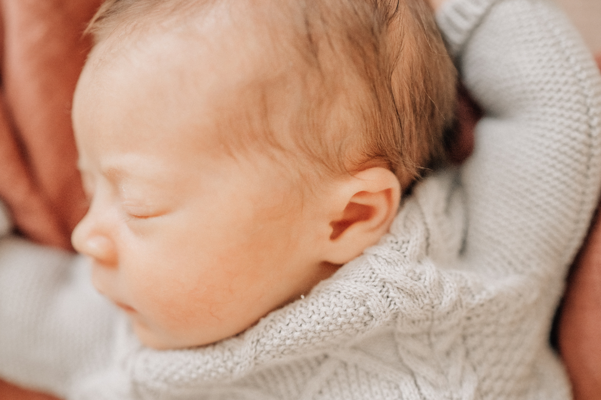 Close up newborn baby photos of tiny ear and soft knit sweater.