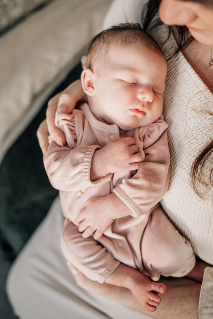 In-home newborn photography ideas with sleeping baby resting on parent’s chest.