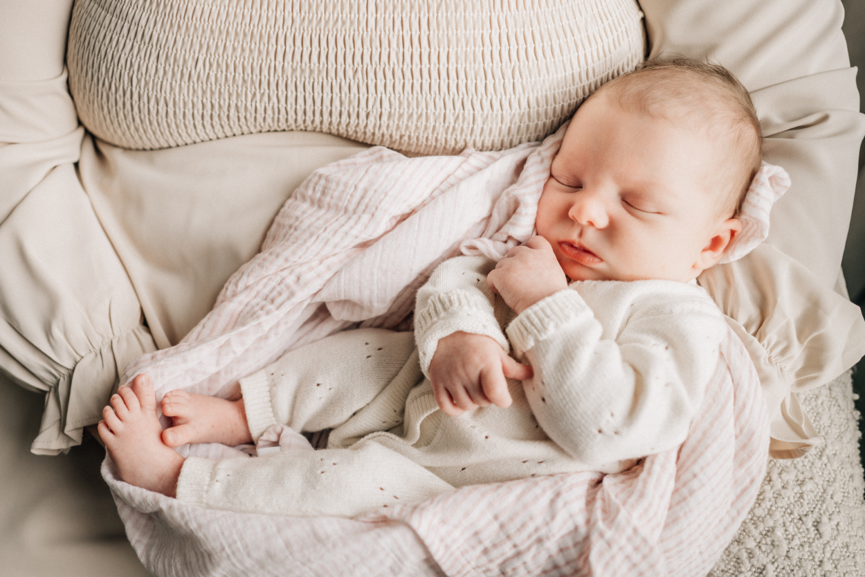 In-home newborn photography ideas featuring sleeping baby wrapped in soft neutral blanket.