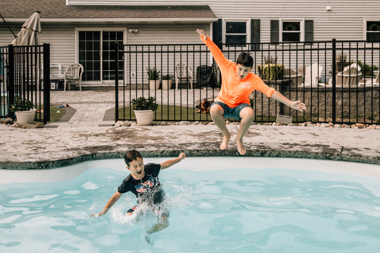 Kids jumping into pool during a backyard photoshoot, capturing playful energy and fun summer moments