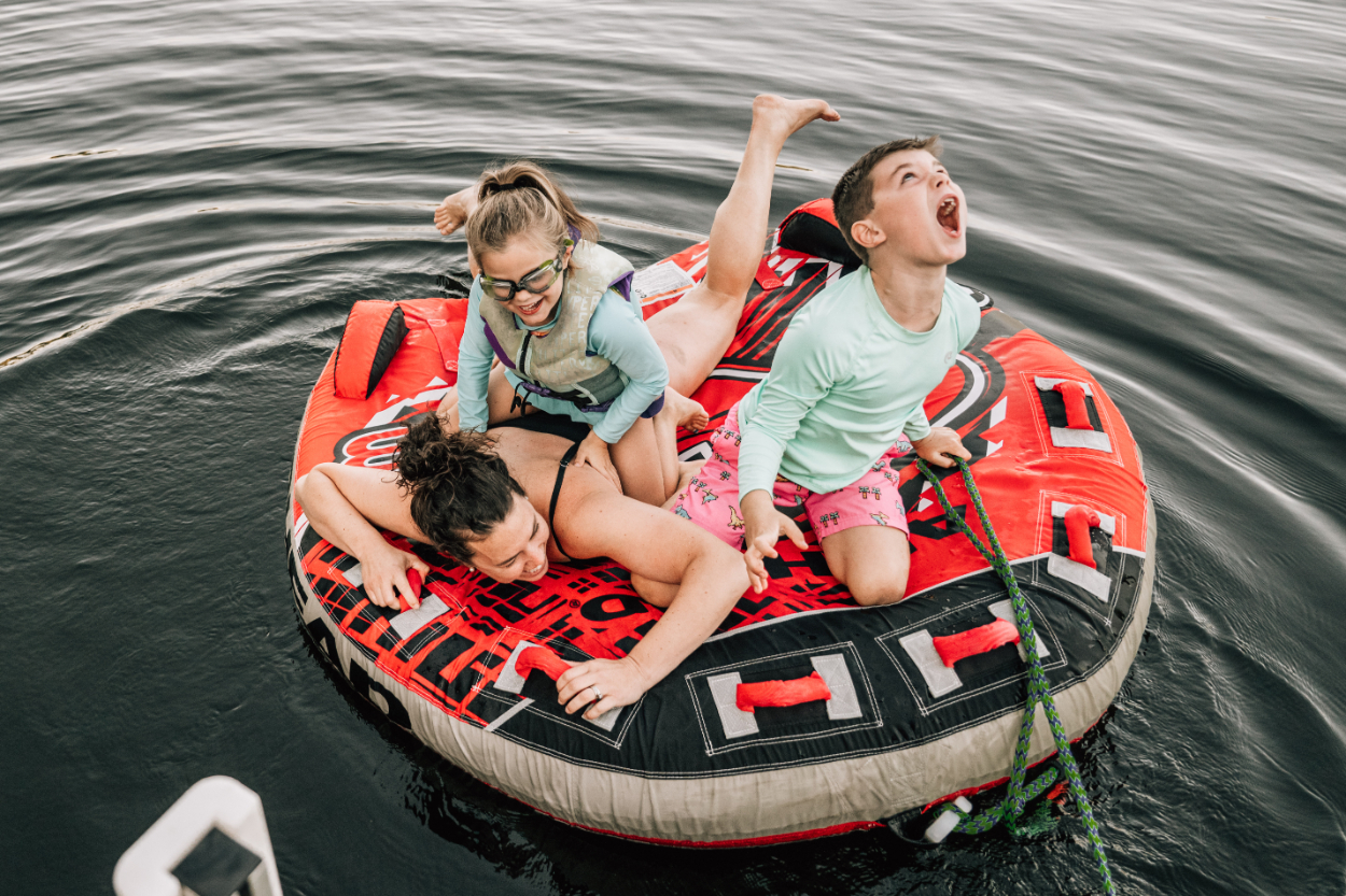 Kids laughing and riding inflatable tube on water, capturing fun, energetic summer adventure moments
