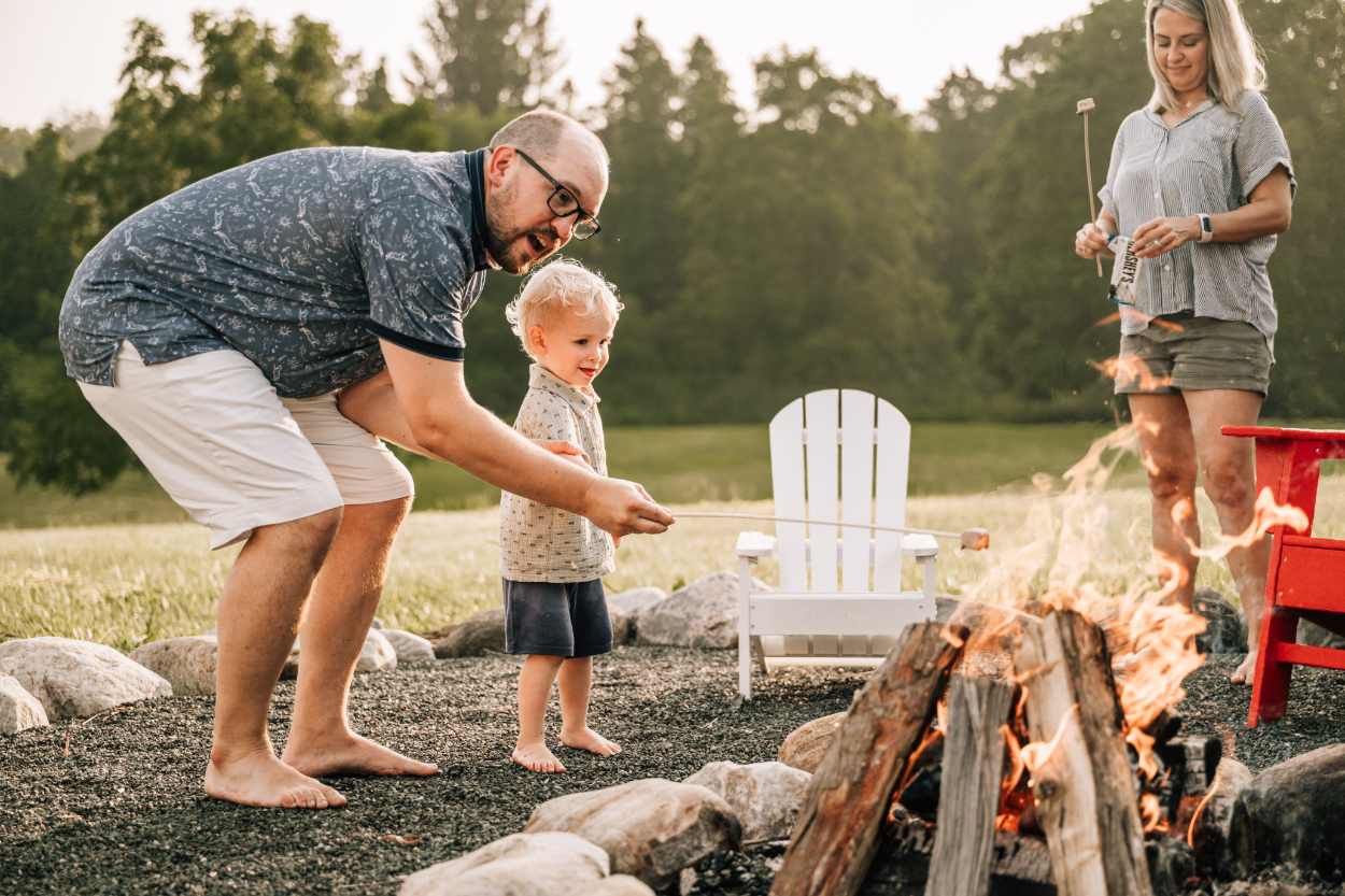 Family gathered around a backyard fire making s’mores, capturing warm, candid evening moments together