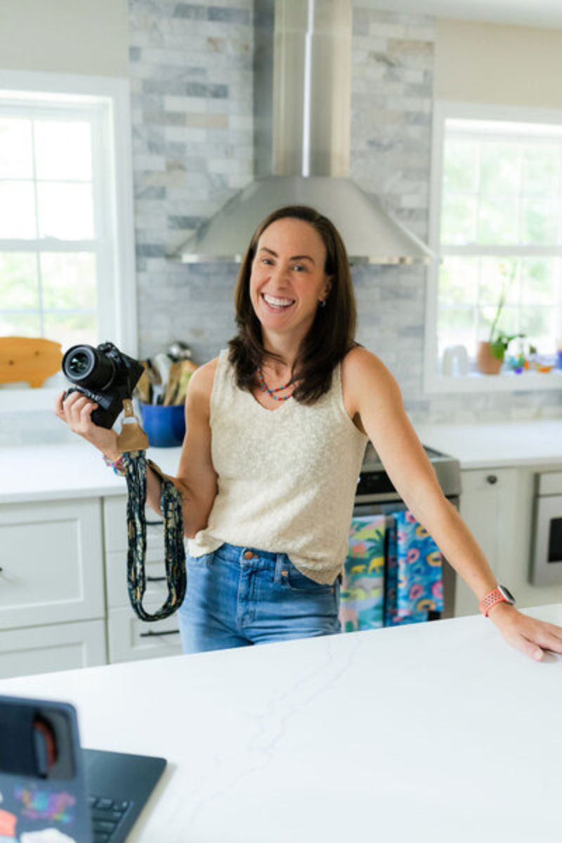 Capital Region NY photographer holding a camera in a bright kitchen studio serving Albany, Saratoga Springs, Schenectady, Troy, Niskayuna, Delmar, Latham, Clifton Park, and surrounding areas.