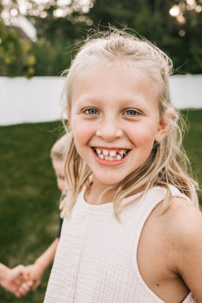 Child laughing while sitting on parent’s lap during playful outdoor family portraits in Albany NY backyard.