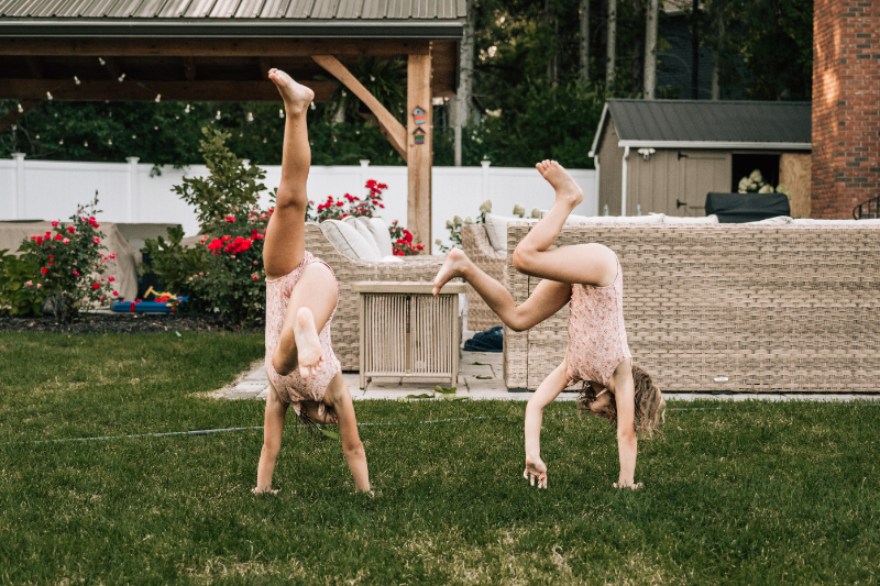 Children doing cartwheels in backyard grass during playful outdoor family portraits in Albany NY.
