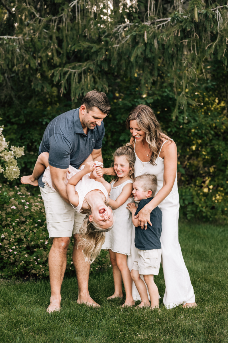 Parents playing with two young children in their backyard during relaxed outdoor family portraits in Albany NY.