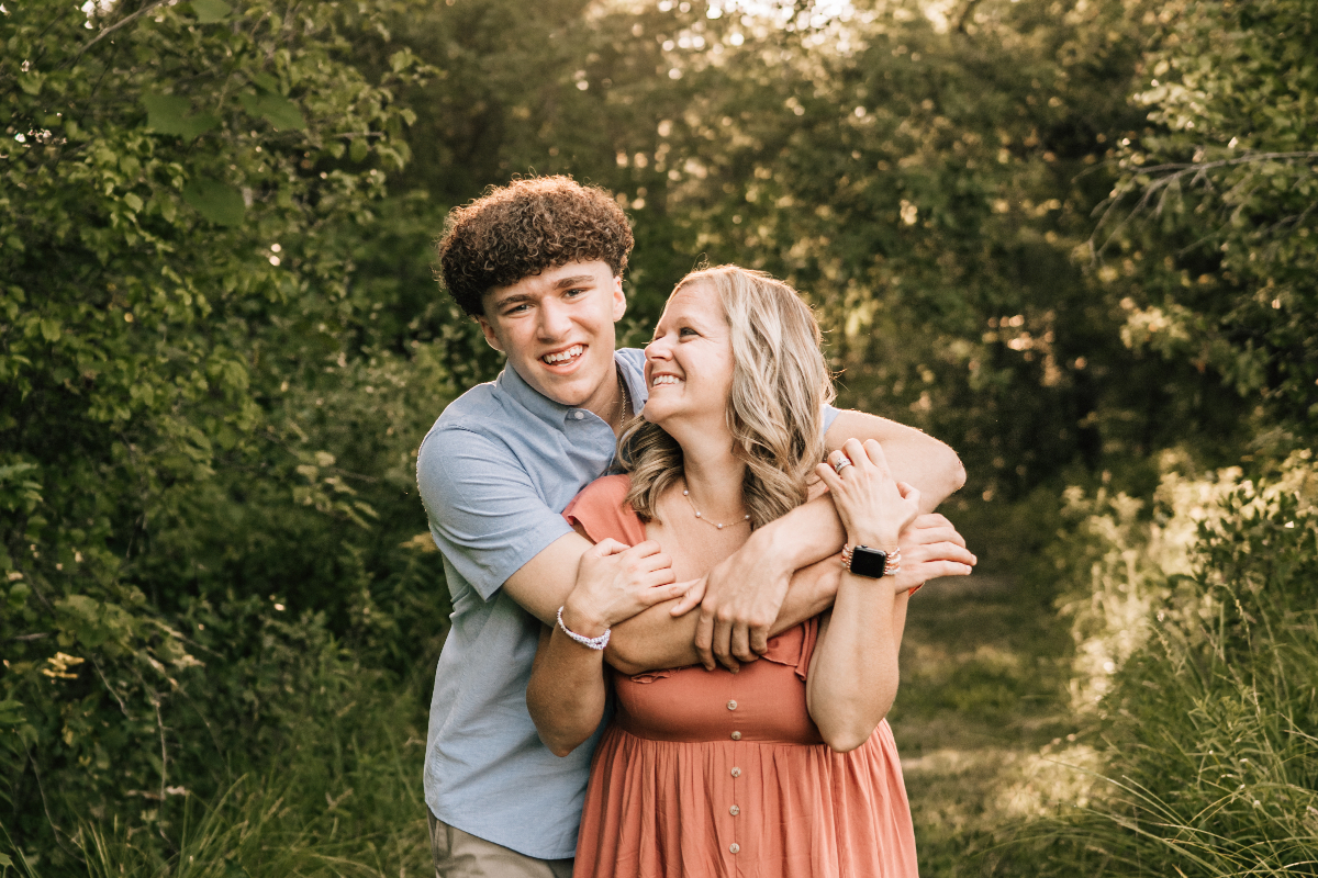 Senior pictures of teen hugging mom, candid close-up showing connection and joy outdoors