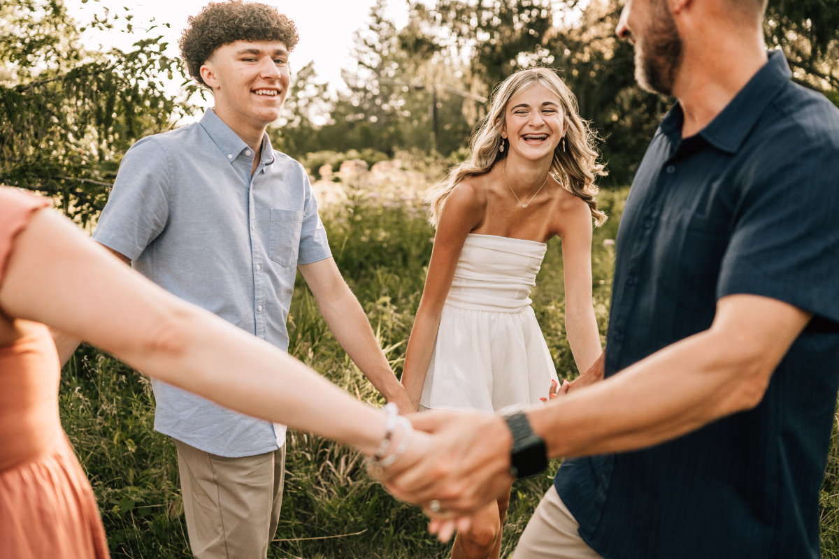 Senior pictures of family holding hands in circle, laughing together during candid outdoor golden hour session