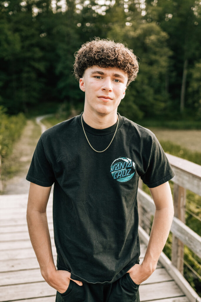 Senior pictures of teen boy standing on wooden path, casual outdoor portrait with natural light