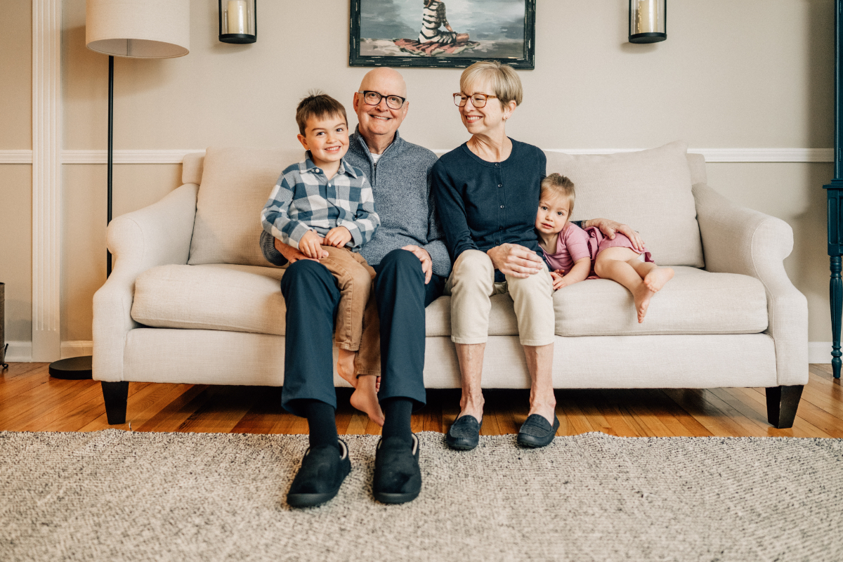 Grandparents and young children sitting together on couch, warm and relaxed multi-generation family moment