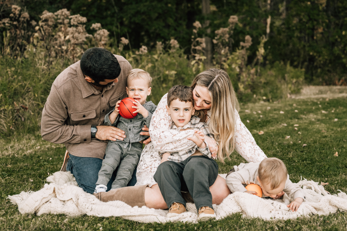 Parents cuddling with their children on a blanket during a relaxed outdoor session.