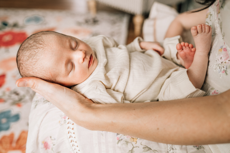 Sleeping newborn cradled in parent’s arms, capturing soft light, tiny details, and peaceful rest.