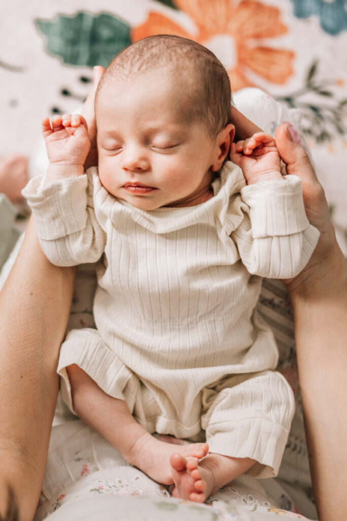 Sleeping newborn in soft outfit during newborn photos at home, capturing peaceful, close-up detail and gentle connection.