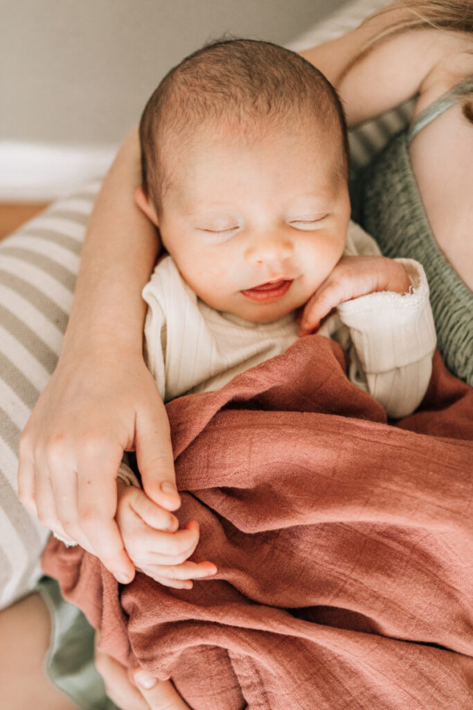 Sleeping newborn wrapped in blanket during newborn photos at home, capturing soft detail and peaceful, connected moment.