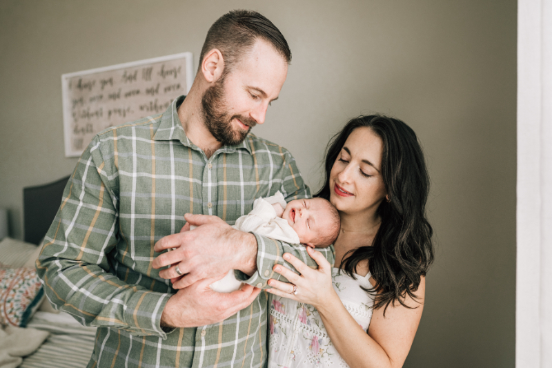 Parents holding newborn together, capturing soft connection, gentle expressions, and a quiet family moment.