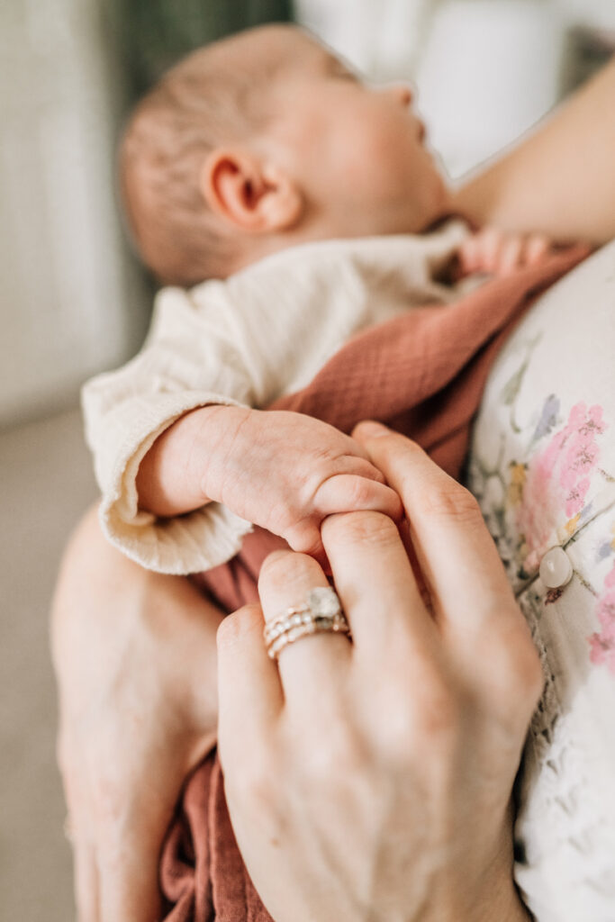 Close-up of parent holding newborn’s hand, highlighting tiny fingers and intimate connection.