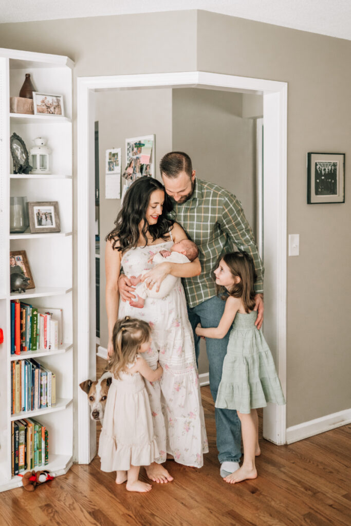 Family of five with newborn and siblings in living room during newborn photos at home, full of connection and warmth.