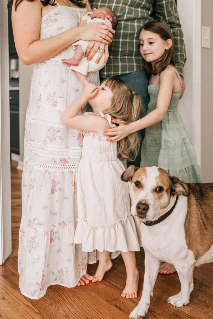 Family with newborn, siblings, and dog during newborn photos at home, showing connection, curiosity, and everyday life.