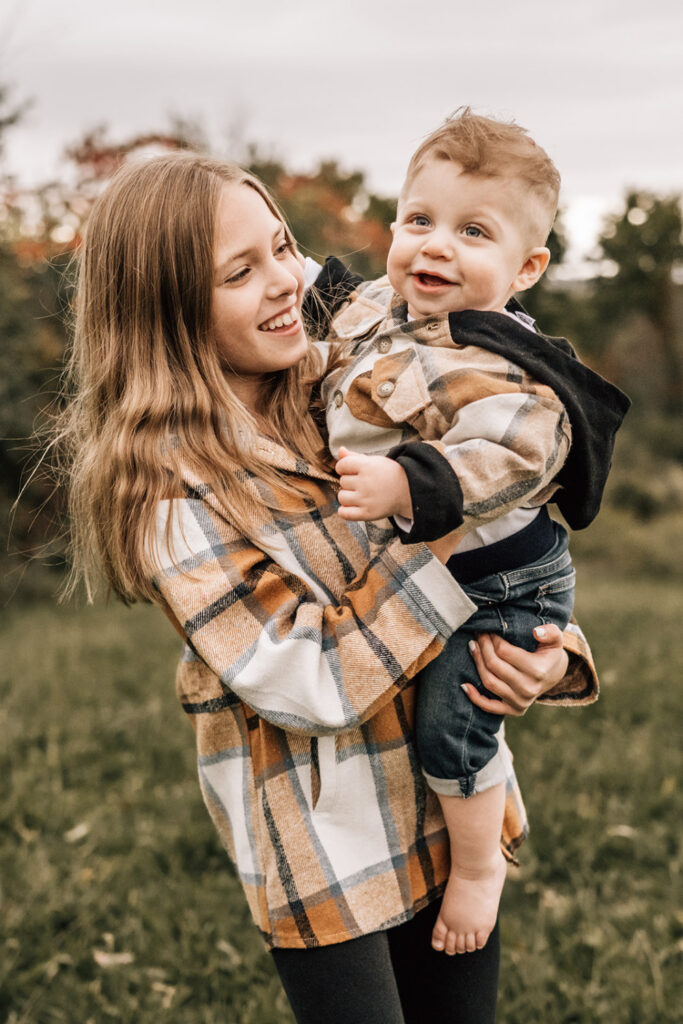 First birthday family photos of a mother cuddling her one-year-old during an outdoor birthday session.
