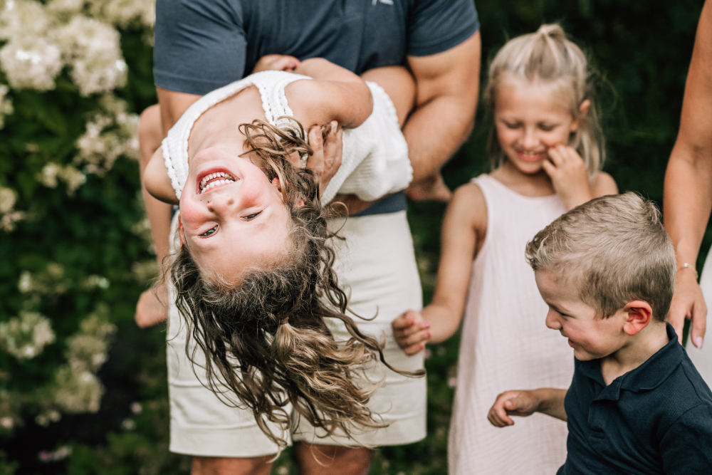 Lifestyle family photography captures siblings laughing and playing together during a fun, relaxed outdoor family session.