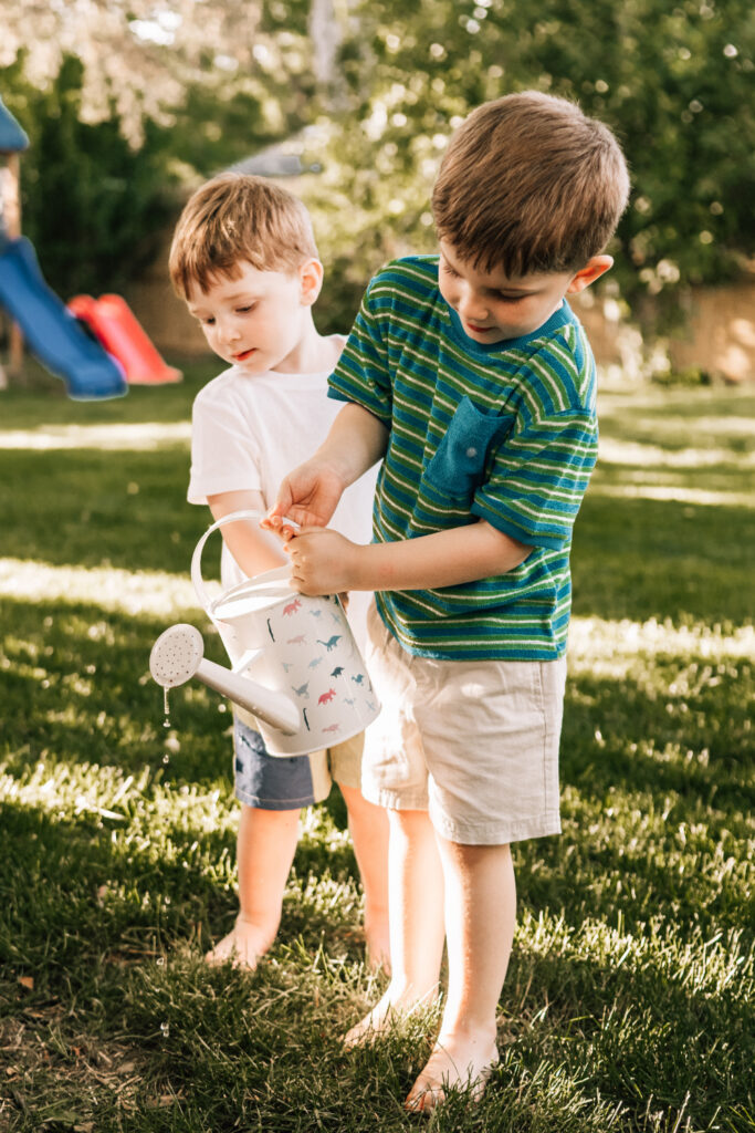 Outdoor family photo ideas with two young brothers playing together in a sunny backyard during family session.