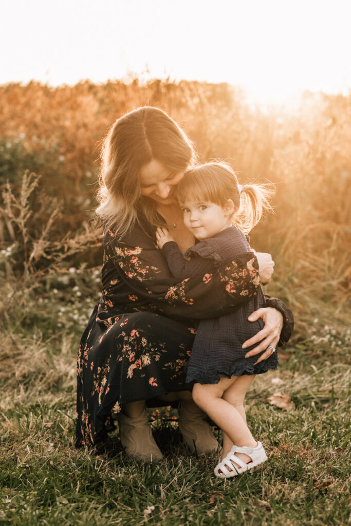 What to wear for family photos, mother hugs her toddler during a golden fall family session outdoors.