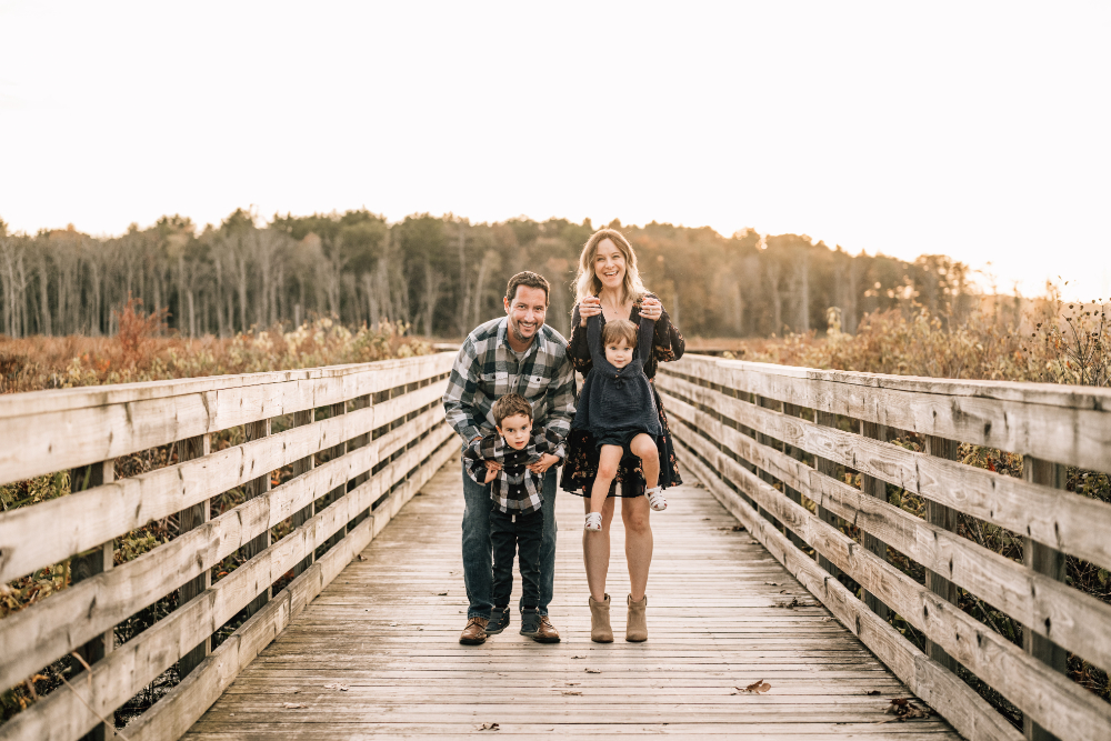 What to wear for family photos, family walks together on a wooden bridge during a golden fall family session.